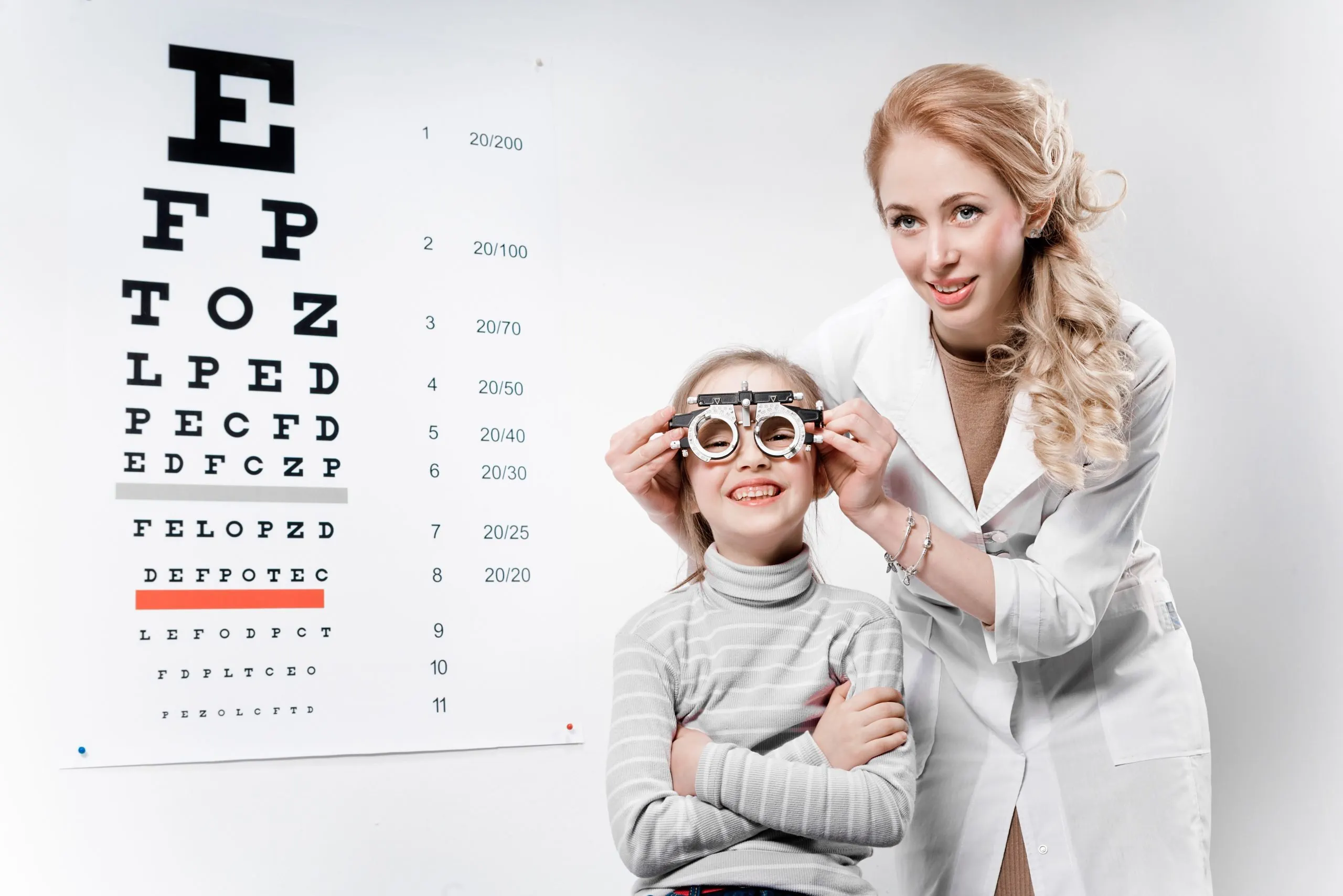 Young girl smiling while undergoing eye test with phoropter