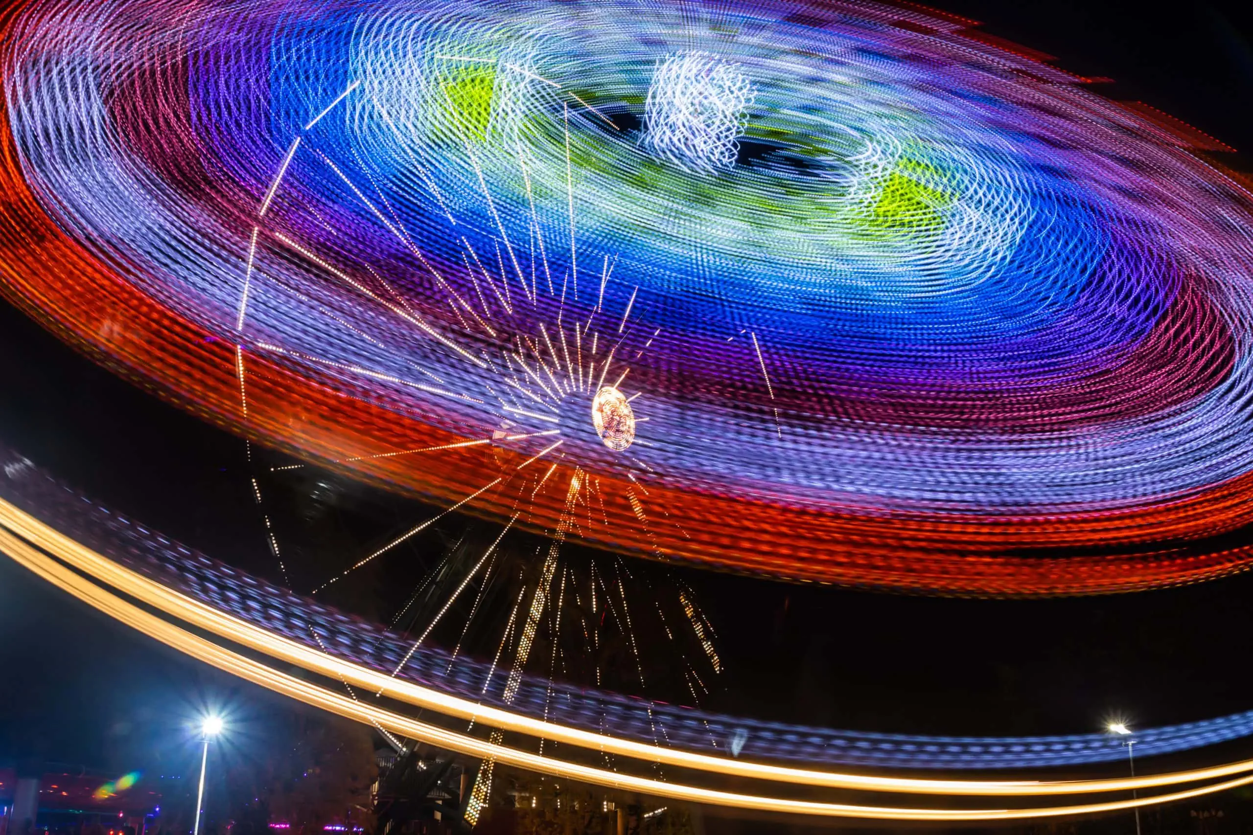 Two rides in motion in amusement park, night illumination. Long exposure.